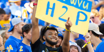 Students holding H2P sign at football game